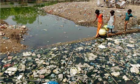 Children carry drinking water as they pass through a polluted pond in Allahabad,