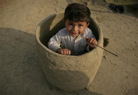 An internally displaced child sits in a mud oven outside his family tent at a camp for flood victims in Charsadda, northwest Pakistan An internally displaced child sits in a mud oven outside his family tent at a ca