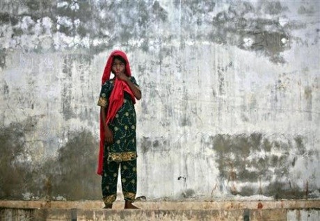 Zahida, a nine-year-old girl displaced by floods stands amidst a wall with rainw