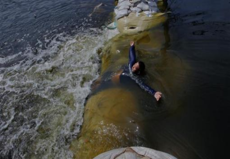 A soldier plays amid water rolling past sandbags into the city near the military airport in the Don Muang airport area of Bangkok on November 9, 2011. REUTERS/Sukree Sukplang A soldier plays amid water rolling past sandbags into the city near the military